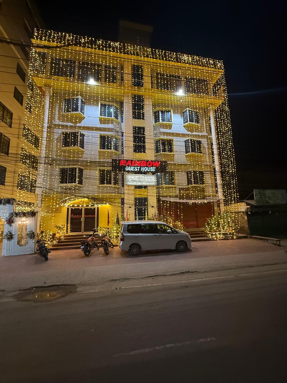 Rainbow Guest House building lit up with string lights at night